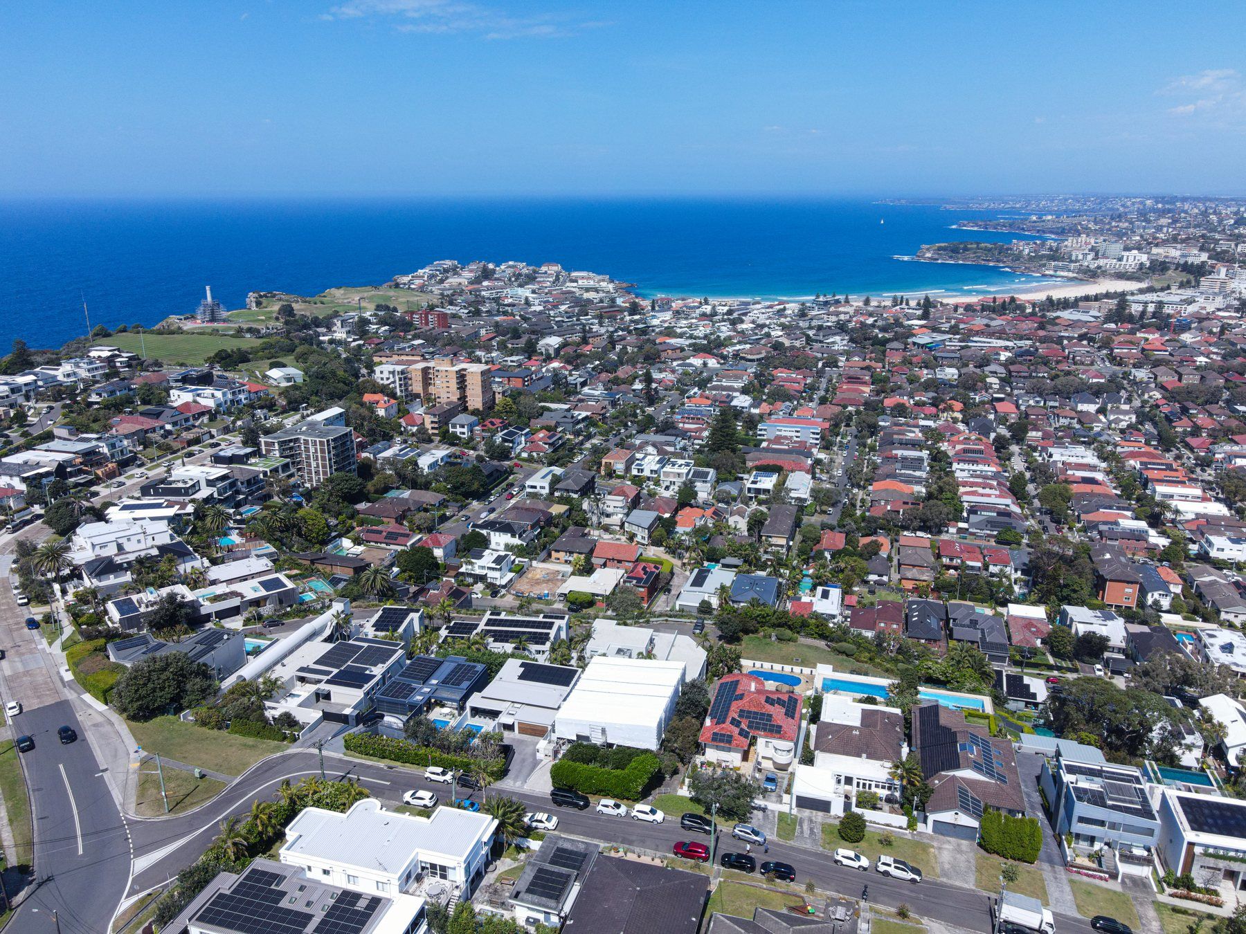 Wide aerial looking along the coast, the wrapped home among the streets below