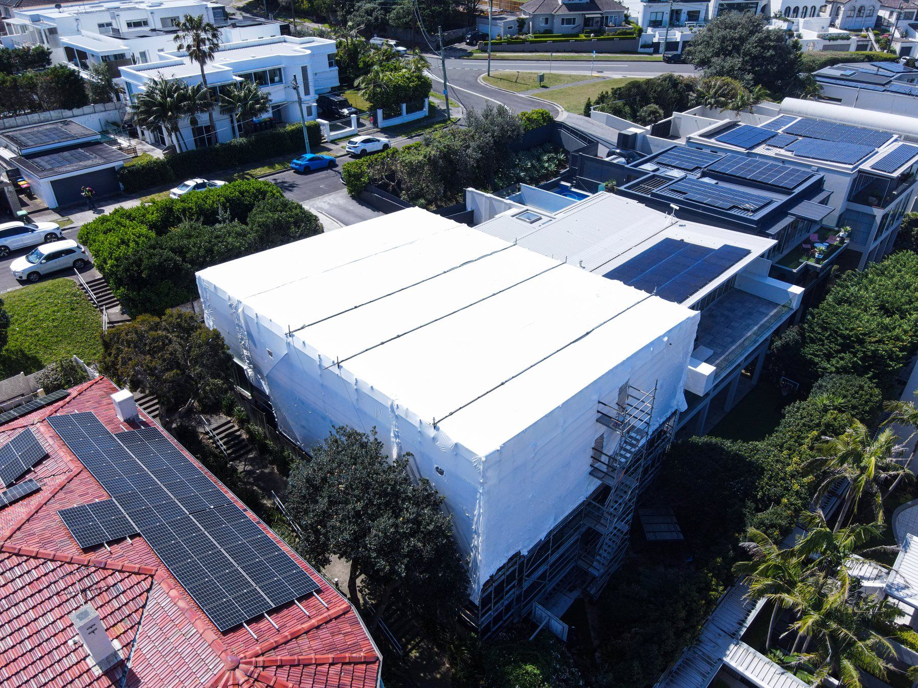 Oblique aerial of the wrap and stair tower beside a tiled roof, palms and the street below