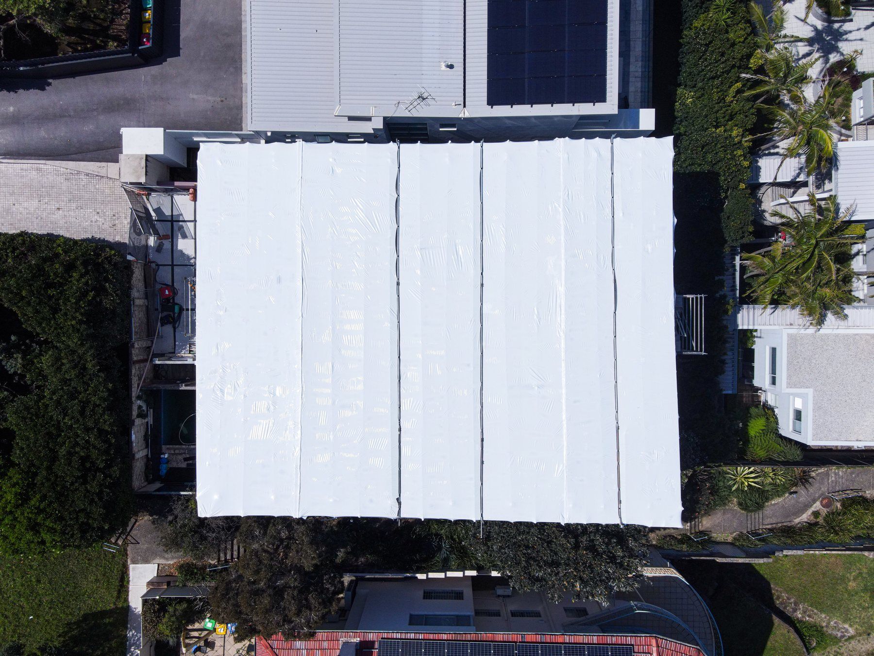 Top-down view of the white shrink wrap roof between the neighbouring houses