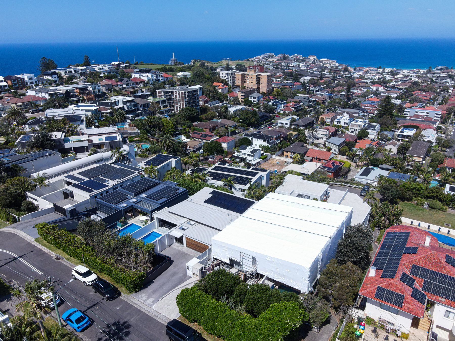Wide aerial of the wrap on its street, the suburb running out to the ocean
