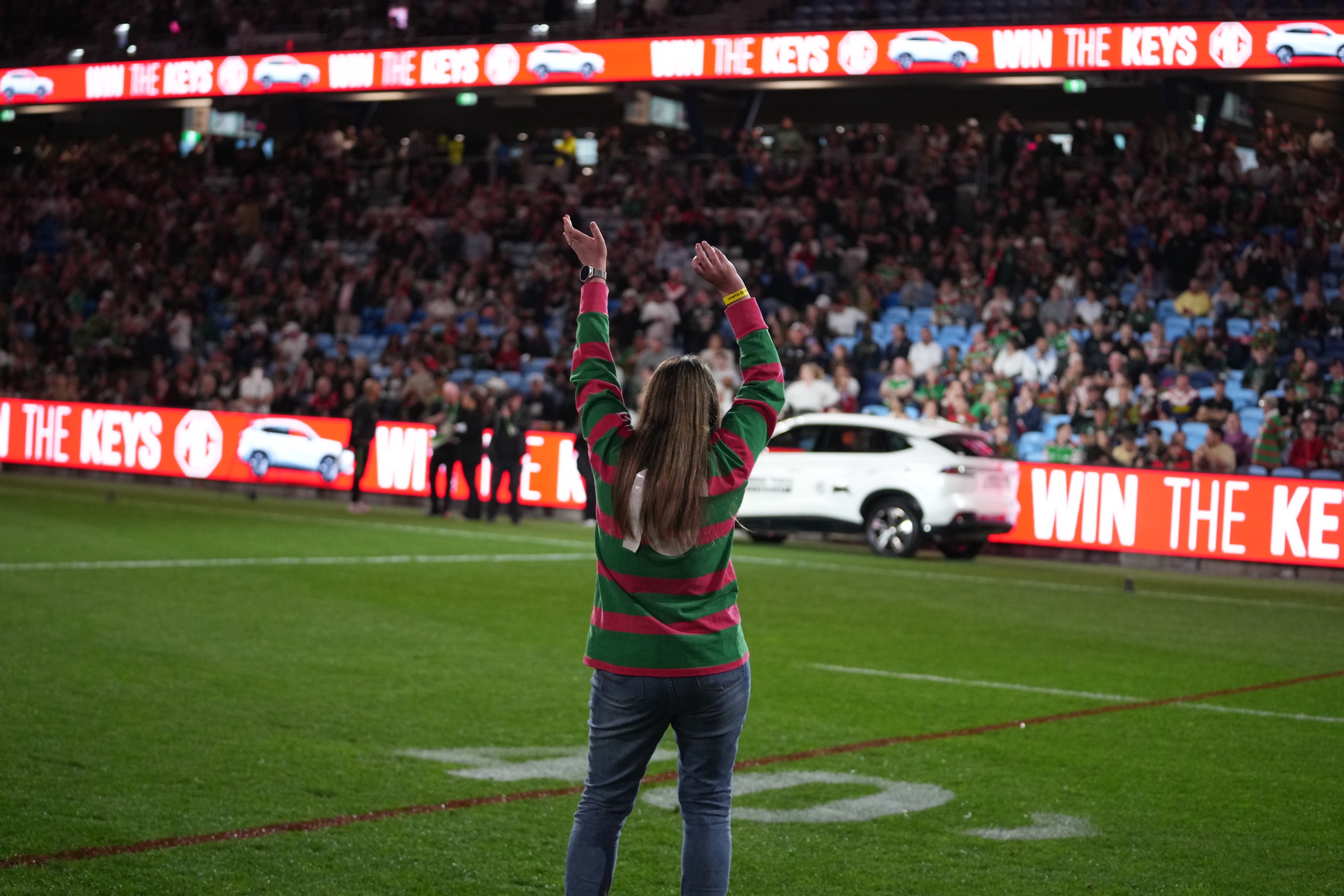Rabbitohs fan celebrating on the field as the MG HS Hybrid+ is driven out, Allianz Stadium